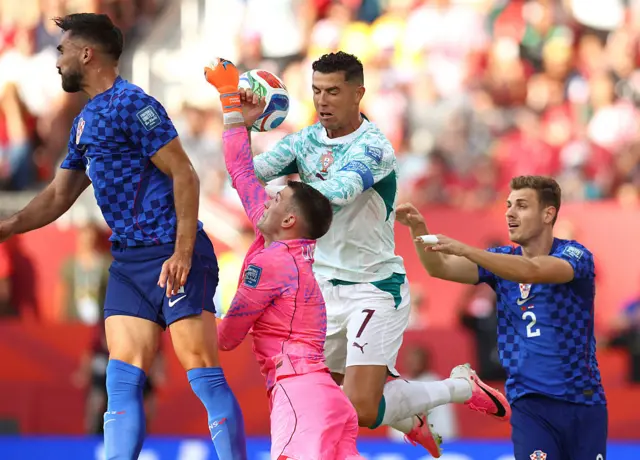 Dominik Livakovic and Cristiano Ronaldo challenge for a cross