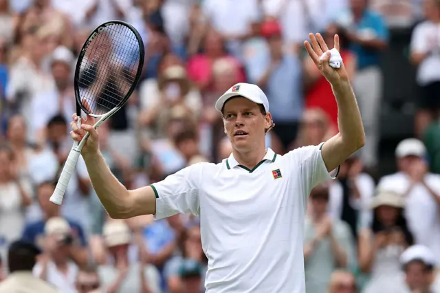 Jannik Sinner holds up a tennis racquet