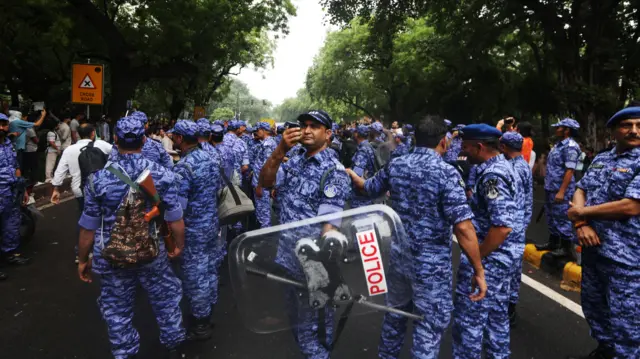 Police officers stand guard as supporters of the Cockroach Janta Party (CJP) gather for a protest march toward Parliament
