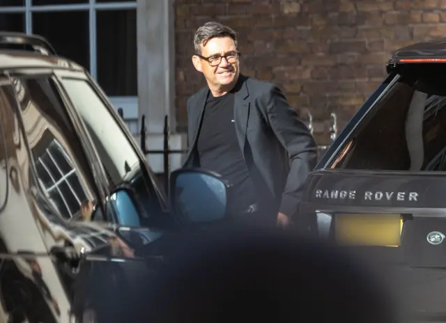 Andy Burnham stood in between two black cars