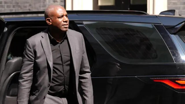 David Lammy, in a grey suit, gets out of a black car