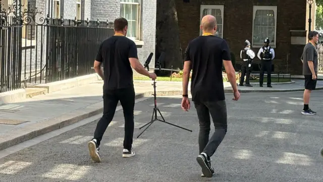 Two men carrying a microphone stand