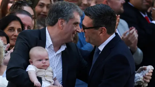 Burnham and Rotheram hug while the latter holds a baby
