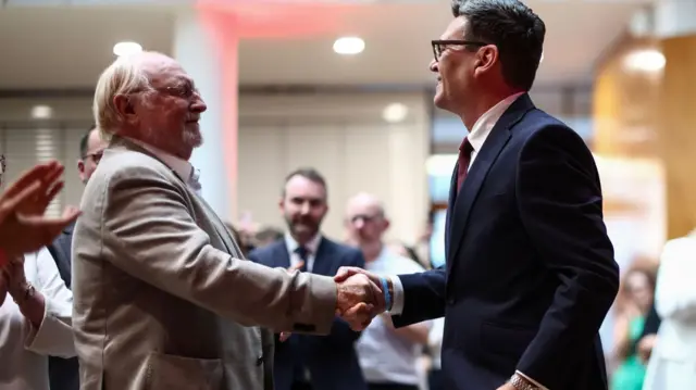 Lord Neil Kinnock and Andy Burnham, two men, shaking hands