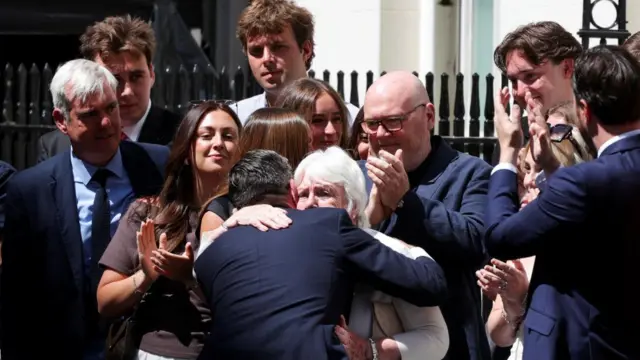 Burnham hugs his mum while people watch and clap