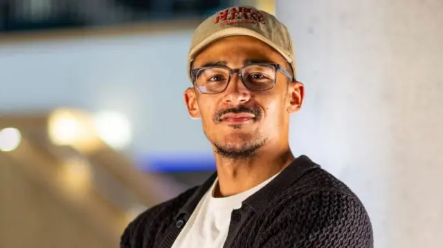 Aston Higton, who runs Little Vics Deli in Derby, with one shoulder away from the photo frame and looking into the camera
