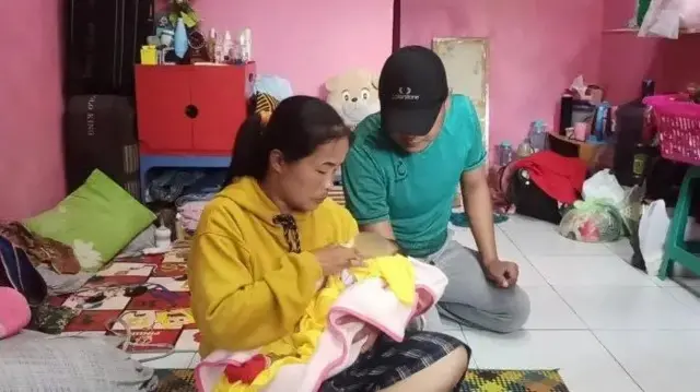Erika cradling her baby in a room