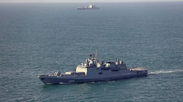 A view of the sea with a Russian frigate in the foreground and a Royal Navy ship further away in the background