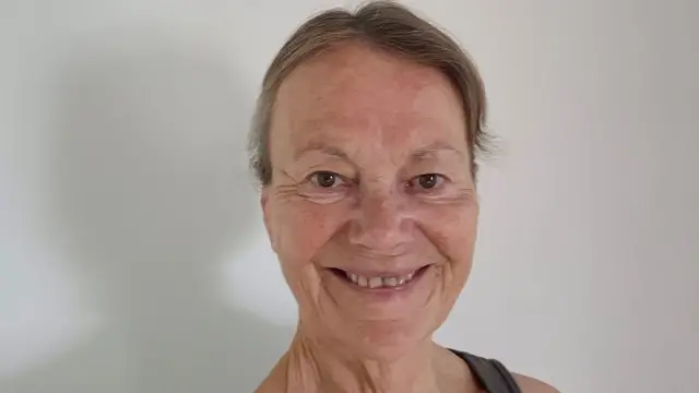 A woman smiling and looking at a camera while taking a selfie