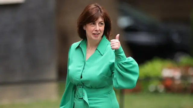 Lucy Powell, wearing a green outfit and giving a thumbs up.