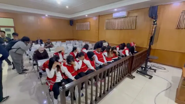 A man taking a photo of people sitting in court
