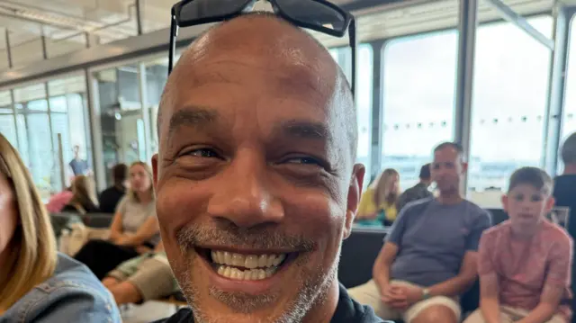 A man sitting in a waiting area at an airport.
