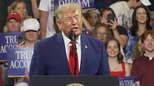 Headshot of Trump with lots of kids smiling behind him