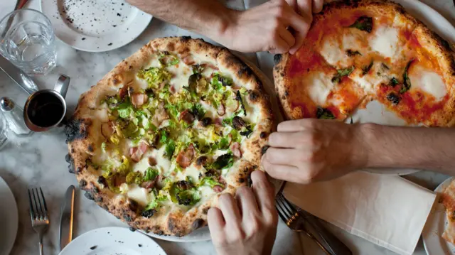 People reaching for pizza