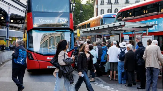 People waiting to board a double decker London bus.