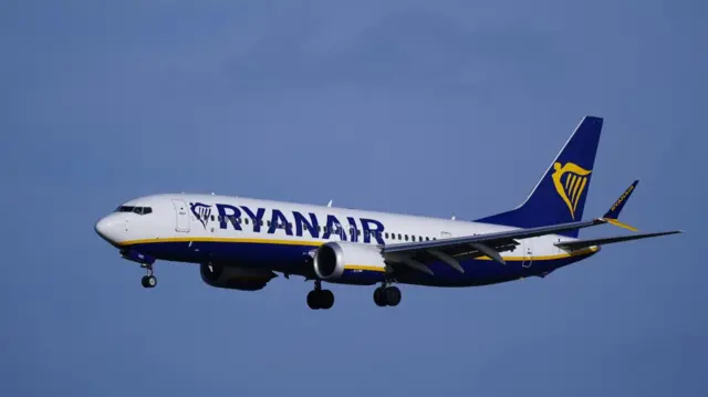 A Ryanair plane in the air with its landing gear deployed.
