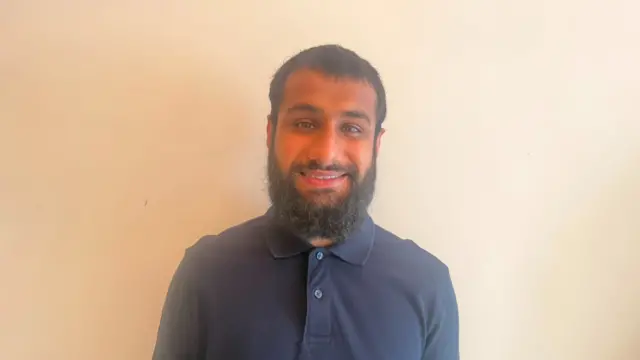 Mohammed Numaan Azam smiling for the camera in front of a blank background.