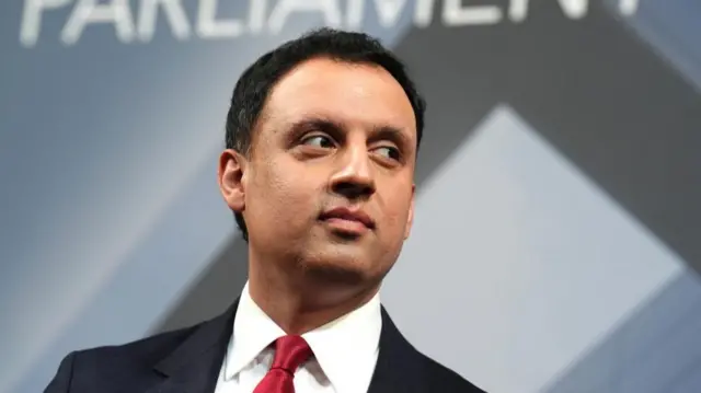 Anas Sarwar wearing a suit and tie and looking to the right