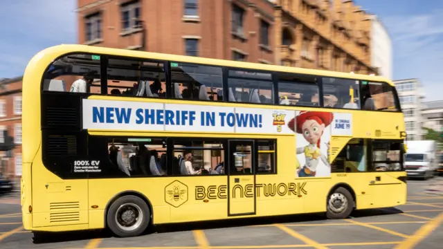 Yellow Bee Network bus in Manchester with an advert for the new Toy Story movie on the side reading "New Sheriff In Town"