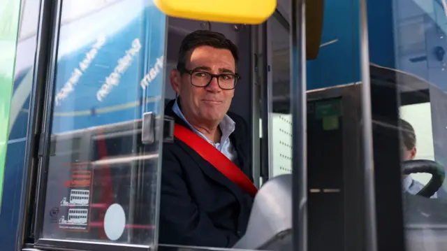 Andy Burnham smiles from inside a bus
