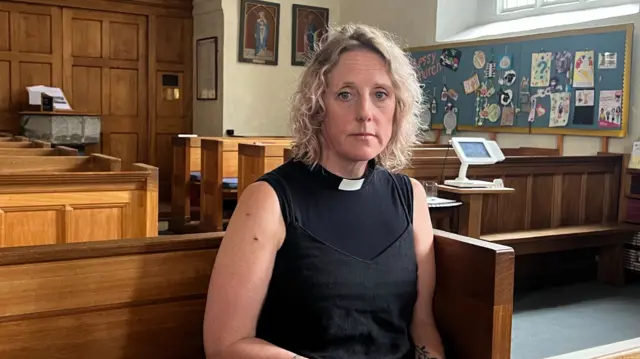 Reverend Jo Parrott sits on a church pew