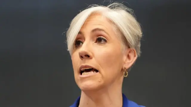 Daisy Cooper has short grey hair and wears a blue top