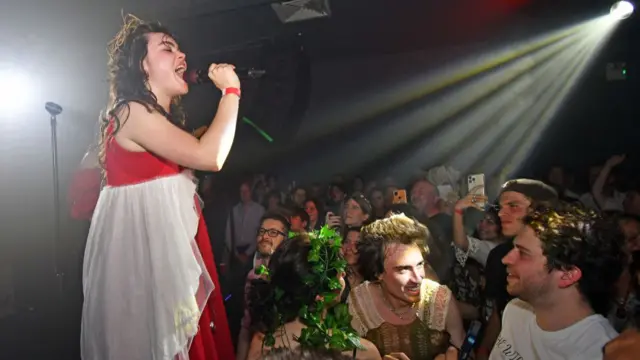 Woman in red dress signing in front of crowd