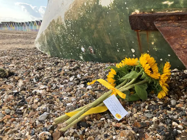 Sunflowers with a note that have been put on the beach