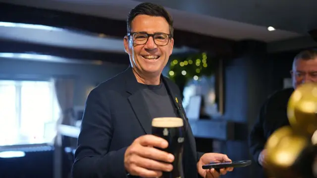 Andy Burnham holds a pint of Guinness in a pub