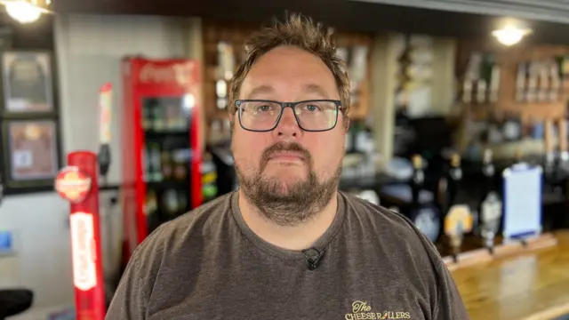 Shaun Tippins, a man, wearing glasses, while standing in a pub