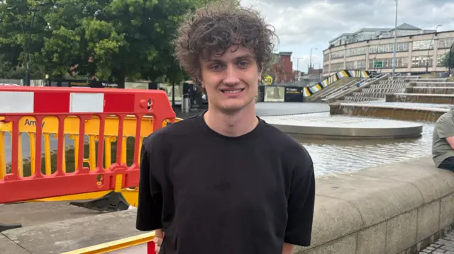 Jack Brisbane stands next to a fountain in Sheffield