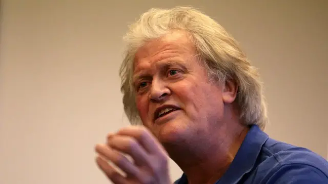 Tim Martin wearing a blue polo while speaking.