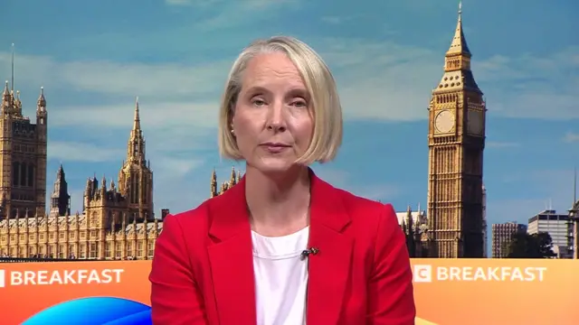 Emma Reynolds, a woman wearing a red blazer.