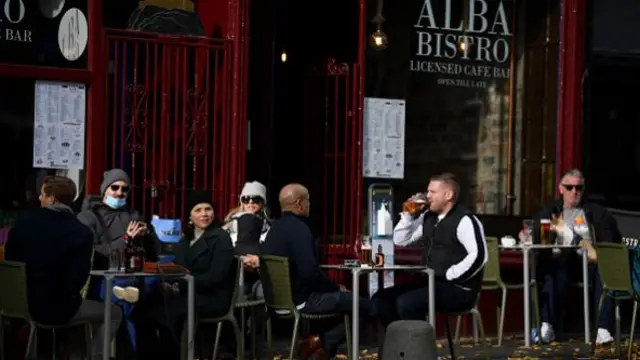 People sit outside a venue called the Alba Bistro, some of them have drinks