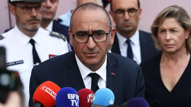 Laurent Nuñez speaking into microphones as people stand behind him