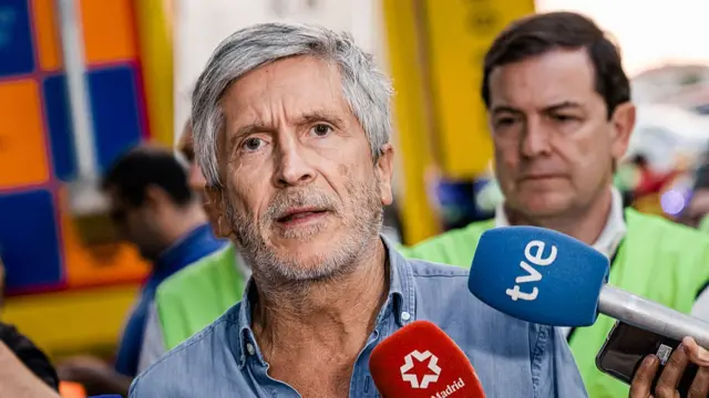 Interior minister Fernando Grande-Marlaska in a denim shirt with the two top buttons opened as he speaks to the press