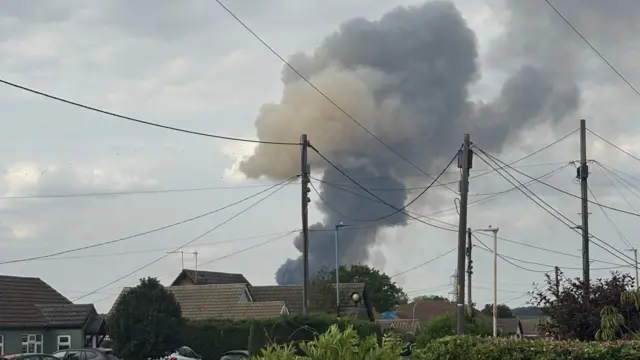 Smoke rising above a line of properties.