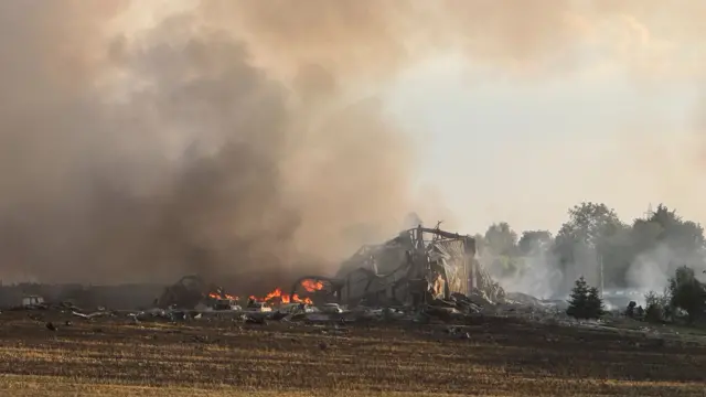 Fire burning around a collapsed building on a field