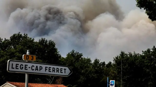 Smoke rises over a pine forest during a wildfire spreading in Cap Ferret, in Lege-Cap-Ferret, south-western France, 24 July 2026.