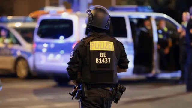 A police officer walks in Berlin with the word "polizei" written in yellow on his back