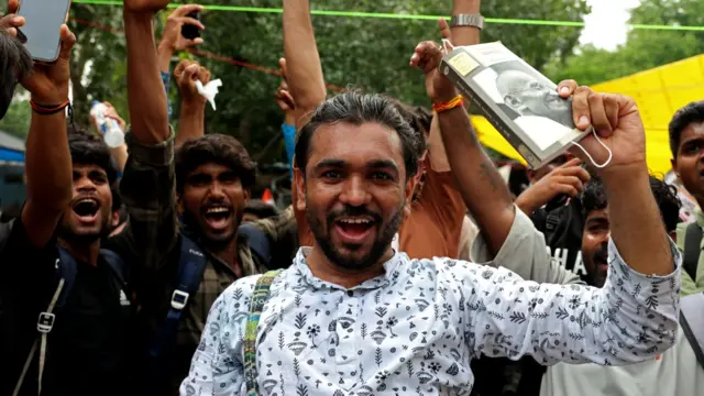 A supporter of India's Cockroach Janta Party (CJP) celebrates as he holds a book with Mahatma Gandhi's portrait on the cover after India's Education Minister
