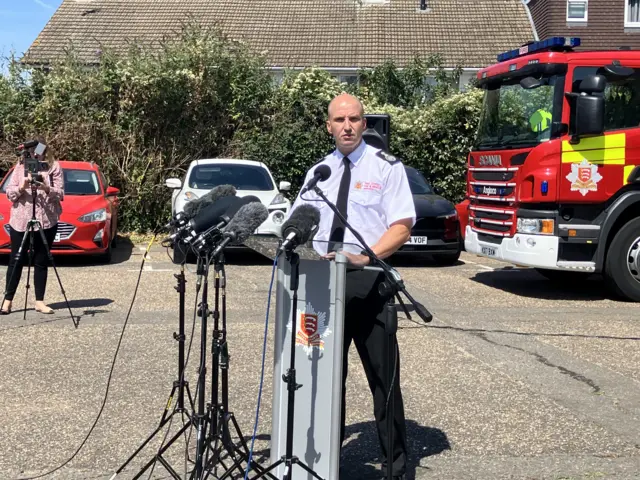 Firefighter speaks at a press conference from behind a podium