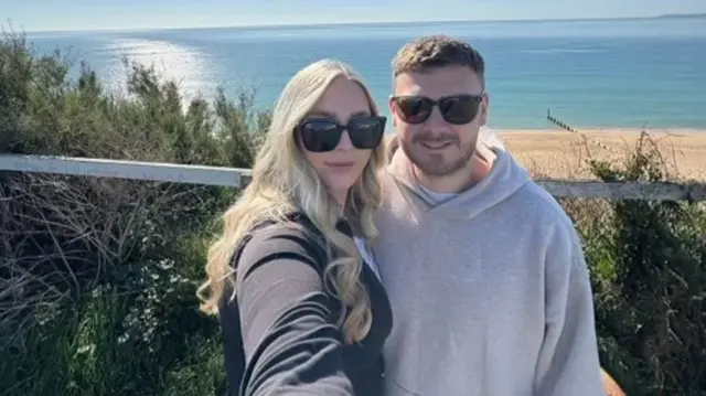 Maisie and Caleb wearing sunglasses with a beach in the background