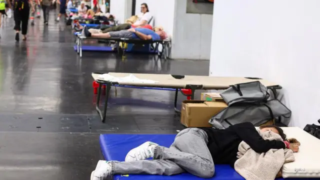 A woman rests at the Bordeaux-Lac Exhibition Centre, which has been turned into a shelter for people displaced by a wildfire.