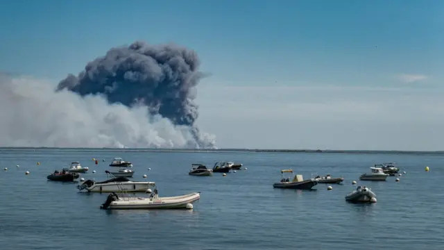 Smoke from wildfires spreading in the Cap-Ferret peninsula is seen from the Arcachon bay in Arcachon, south-western France, 24 July 2026