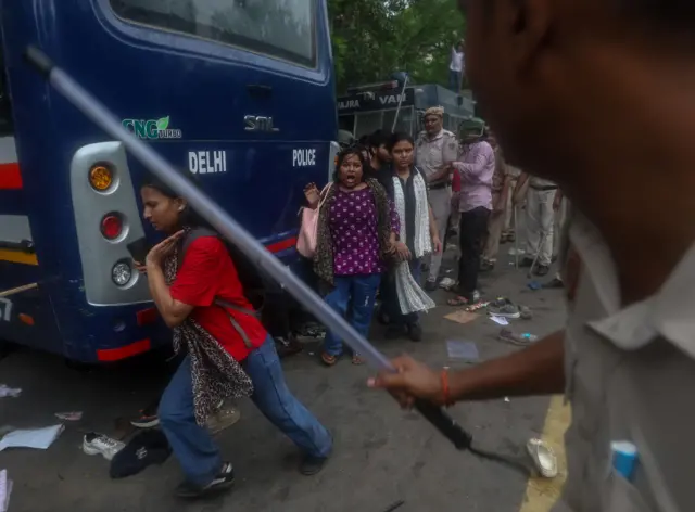 Police hitting a woman with a stick