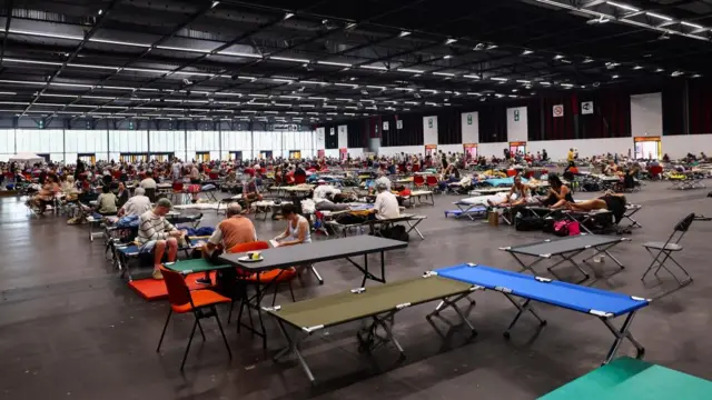 Evacuated residents rest at the Bordeaux-Lac Exhibition Centre, which has been turned into a shelter for people displaced by a wildfire burning nearby amid worsening drought conditions following a heatwave and water shortages across much of France, in Bordeaux, France, July 25, 2026.