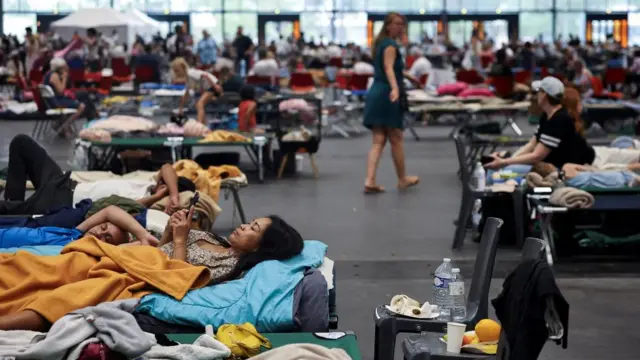 A woman looks at her phone at the Bordeaux-Lac Exhibition Centre, which has been turned into a shelter for people displaced by a wildfire.