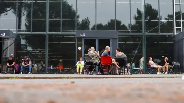 Evacuees wait outside one of the halls at the Bordeaux-Lac Exhibition Centre, which has been turned into a shelter for people displaced by a wildfire burning nearby amid worsening drought conditions following a heatwave and water shortages across much of France, in Bordeaux, France, July 25, 2026.