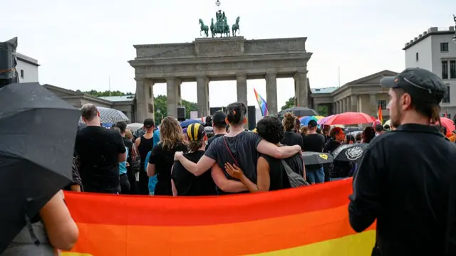 A crowd facing the Brandenburg Gate holding each other